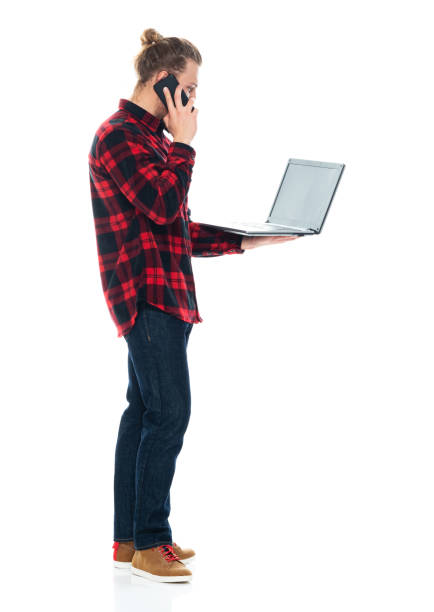 istock Caucasian male standing in front of white background wearing pants and using computer 1226833439