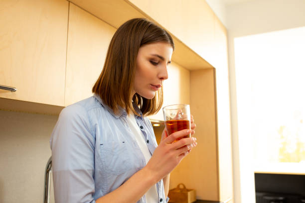 istock Female holding tea and blowing on it, posing in kitchen 1226834306