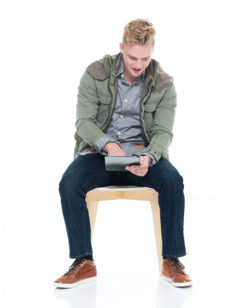istock Caucasian young male resting in front of white background wearing jacket and using digital tablet 1226836738