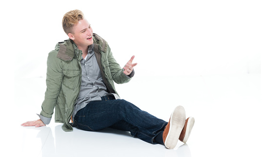 Profile view of aged 18-19 years old caucasian boys sitting in front of white background wearing blazer who is smiling