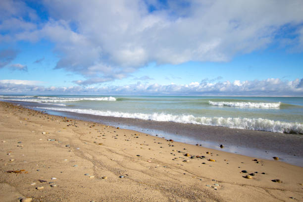 Wide sandy beach on a sunny summer day with waves crashing on the shore.