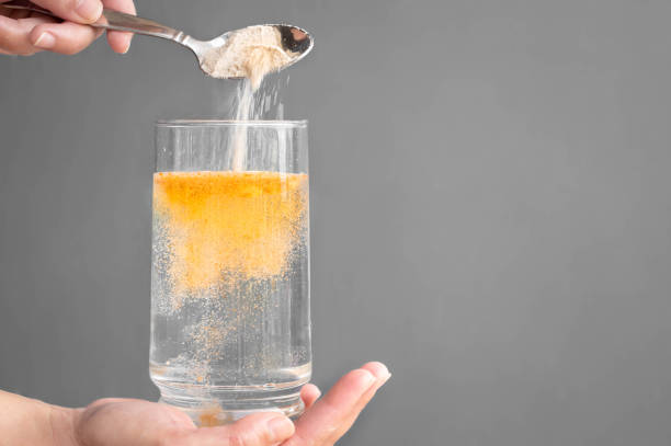 Orange fizzy powder and water glass with copy space. Healthy supplement. A person pouring orange powder into a glass of water with copyspace. dietary fiber photos stock pictures, royalty-free photos & images