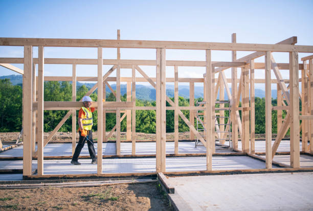 construtor andando com viga de madeira no ombro em um canteiro de obras de madeira inacabada. - construction frame wood accuracy adult - fotografias e filmes do acervo