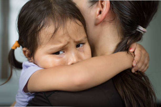 A sad child holding her mother for comfort and safety. A sad little girl hugging her parent to feel safe, tearful. relationship difficulties stock pictures, royalty-free photos & images