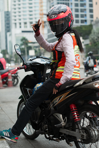 bangkok thailand 8.10.2019 female works as motorcycle taxi driver waiting for costumer giving a thumb up