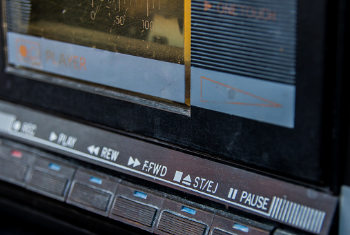 A close up of the buttons to a cassette player on a vintage boom box.