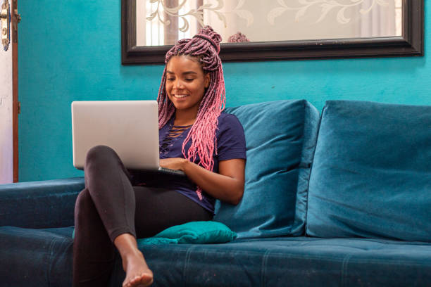 Young black woman with braid using notebook in home room