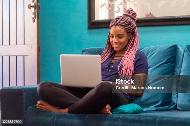 Young Black Woman With Braid Using Notebook In Home Room Stock Photo - Download Image Now