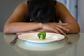 Depressed woman hungry from dieting, sitting in front of a empty plate. Weight loss diet.