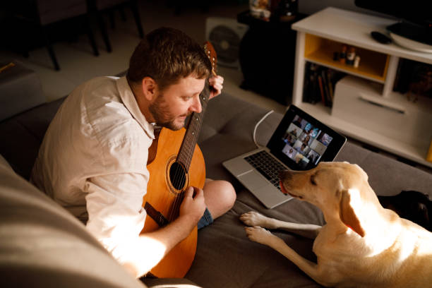 uomo che suona la chitarra acustica in una videochiamata - animals and pets arts and entertainment music foto e immagini stock