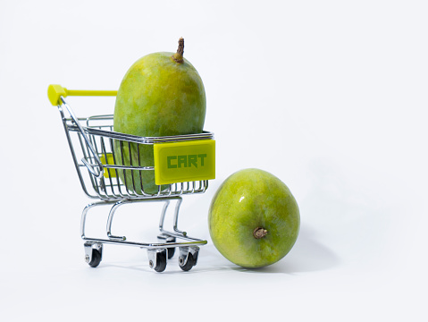 Buying a mango from supermarket Green Raw Kesar mango harvest, Mango fruit and shopping cart isolated on a white background