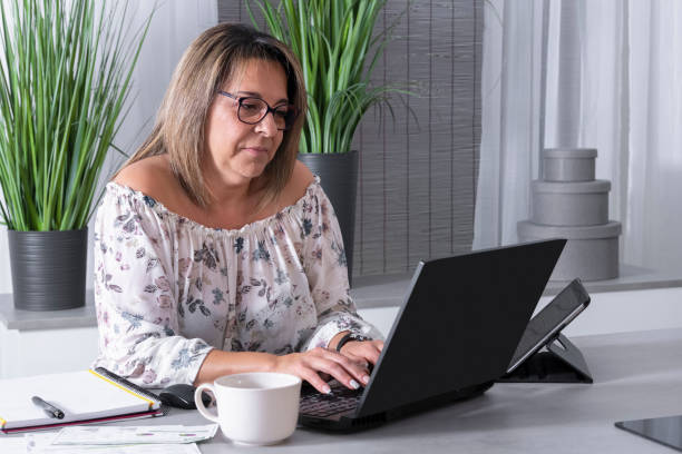 istock mature woman working on a laptop surrounded by a notebook 1226873663