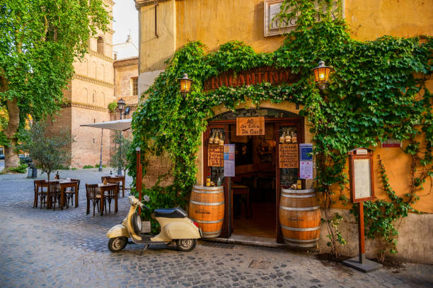 A lovely vintage Vespa in front of a typical restaurant in Trastevere in the historic heart of Rome Rome, Italy, May 22 -- A typical roman restaurant with a scooter in the ancient Trastevere district, the most loved and visited district by the tourists of the ethereal city. Image in HD format. rome italy photos stock pictures, royalty-free photos & images