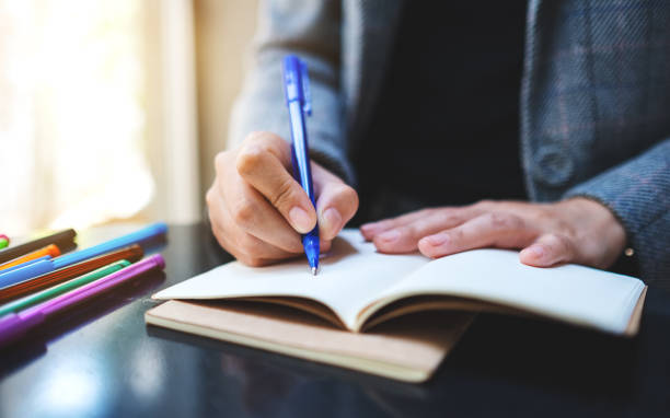 istock a woman writing on a blank notebook with colored pens on the table 1226876257