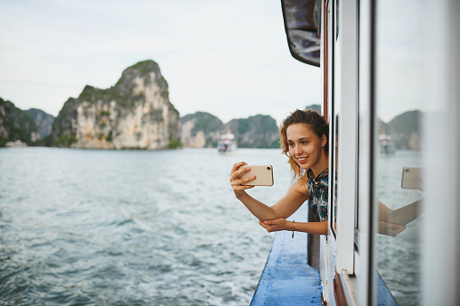 Shot of a young woman taking selfies on a boat ride in Vietnam with her smartphone