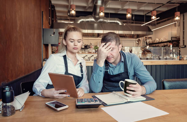 Depressed two entrepreneurs man and woman inside their restaurant overwhelmed by finance problems stock photo