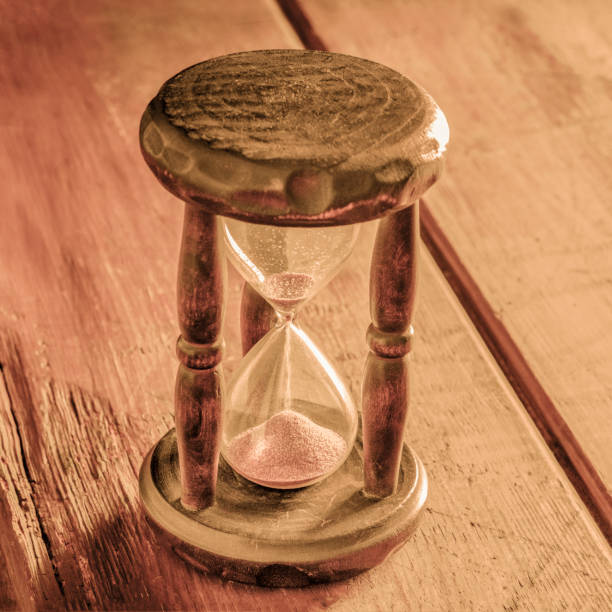 istock Time concept. A vintage hourglass with sand falling through, on a rustic background, toned square image 1226879996
