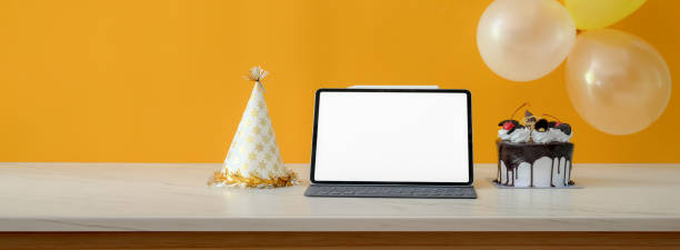 istock Online birthday party concept with blank screen tablet, cake and party hat on white table 1226881233