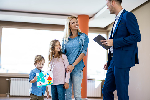 Happy real estate agent communicating with single mother and her kids at new apartment.