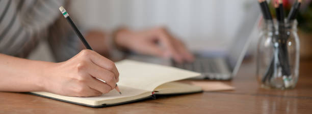 istock Female entrepreneur taking note on notebook while working with laptop on wooden desk 1226881730