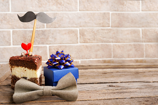 Happy fathers day special cupcake, bow and blue gift box on wooden table, copy space