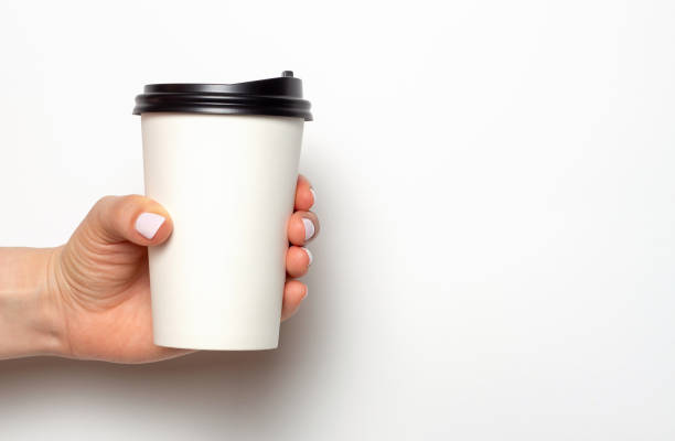 istock A woman's hand with a white manicure holds coffee in paper cup on a white background, copy space 1226884242