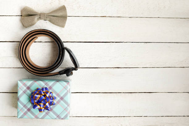 istock bow tie, belt and green gift box on white wooden table with copy space 1226886115