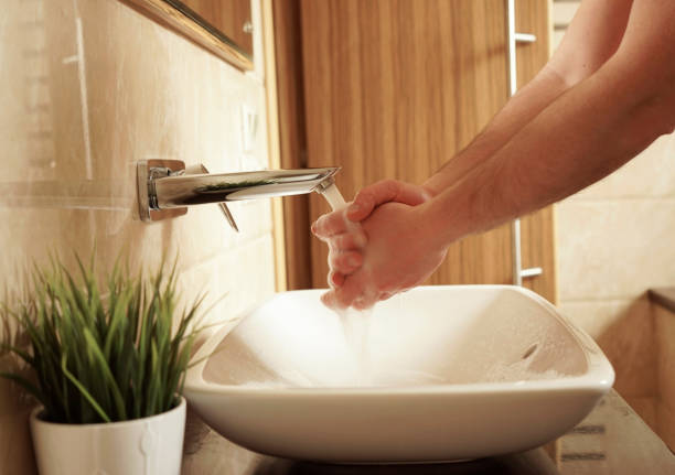 A man washes his hands in the sink in the bathroom,
