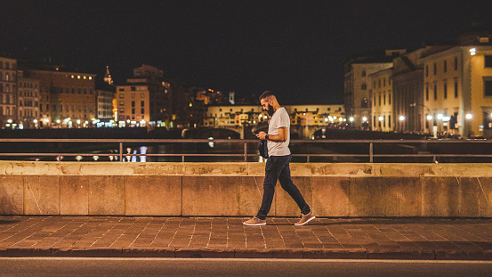 Full length shot of a handsome young man walking along the street while sightseeing in Italy at night