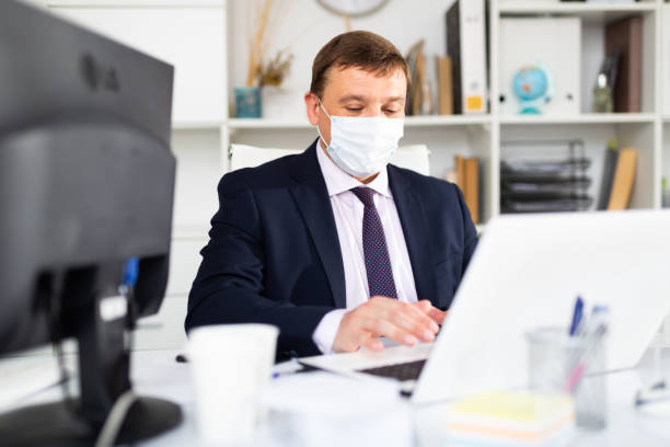 istock Businessman in face mask working on laptop 1226888891