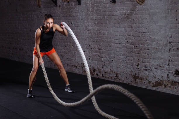 istock Athletic woman doing battle rope exercises at gym 1226890435