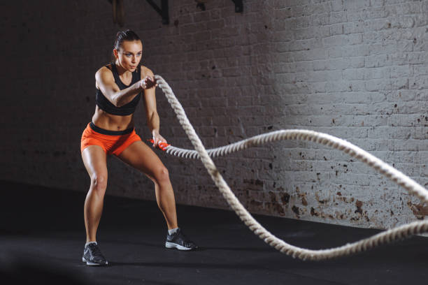 atletische vrouw die de oefeningen van de slagkabel bij gymnastiek doet - veldslag stockfoto's en -beelden