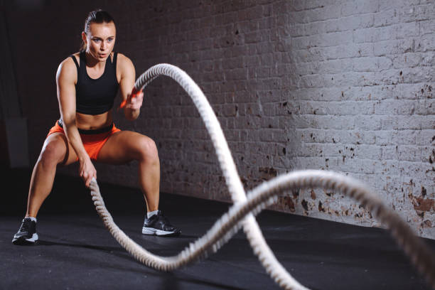 istock Athletic woman doing battle rope exercises at gym 1226890988