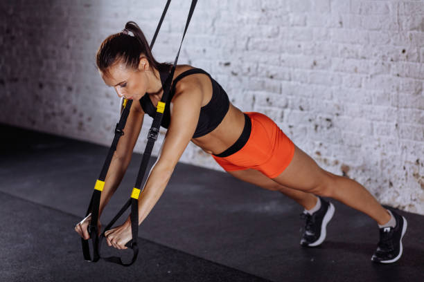 istock Women doing push ups training arms with trx straps in gym 1226893810