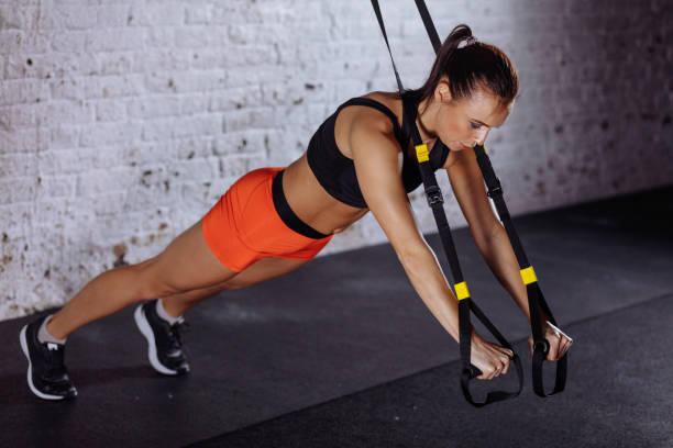 istock Women doing push ups training arms with trx straps in gym 1226893861