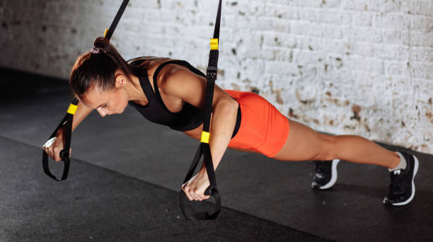 istock Women doing push ups training arms with trx straps in gym 1226893899