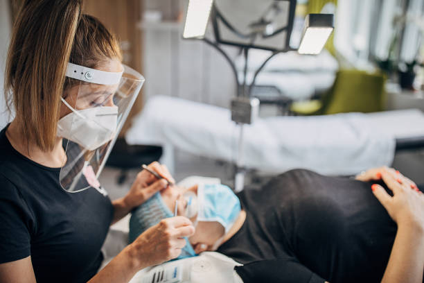 istock Cosmetologist with protective face mask and client in beauty salon 1226894649