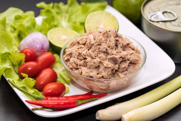 morceaux de thon dans un bol en verre avec salade de légumes frais. - tuna chunks photos et images de collection