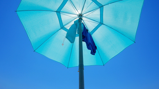 Blue Parasol Against Clear Blue Sky From Low Angle View.