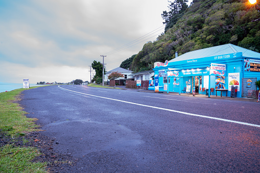 Thames New Zealand - May 24 2020; Bright blue Tararu Store at dawn on cloudy morning on State Highway north of Thames.