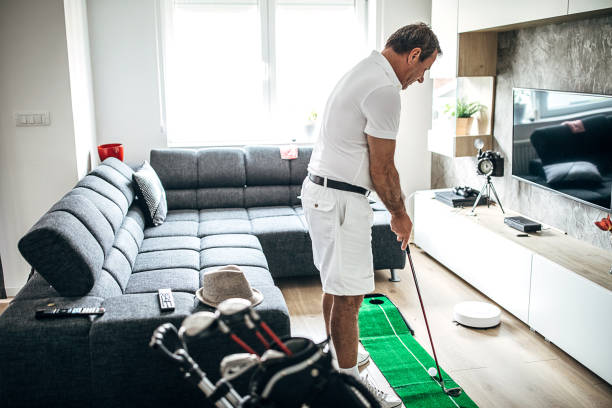 hombre mayor jugando mini golf en la sala de estar en casa - retirement golfer happiness relaxation fotografías e imágenes de stock