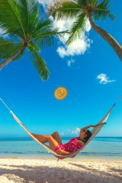 istock Young girl resting in a hammock under tall palm trees, tropical beach 1226902034