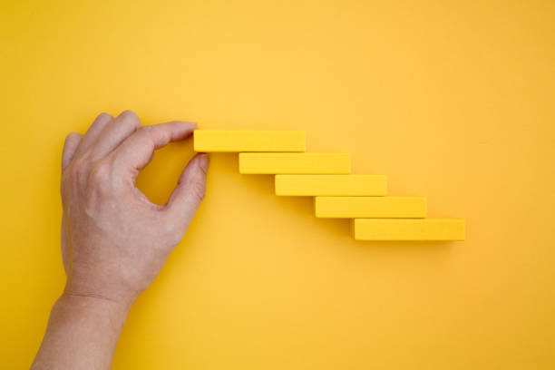 istock hand making stairs with yellow domino blocks 1226904418