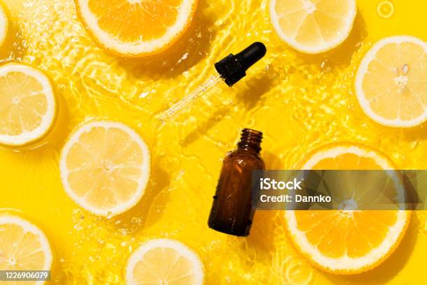 Cosmetic Bottle Product Serum Vitamin C With Orange And Lemon Flat Lay On Yellow Background Clean Water Splashing Stock Photo - Download Image Now