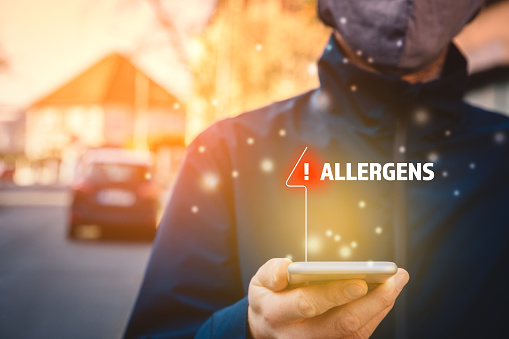 Increased concentration of allergens and polls in the air. Man with mask and smart phone with notification or report about allergens. Modern healthcare concept.