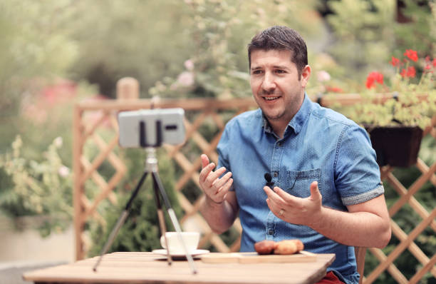 Vlogger man sitting on a table and making a vlog episode stock photo