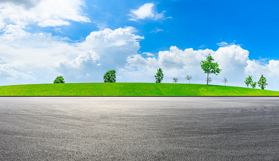 Empty race track and green grass with tree under the blue sky.