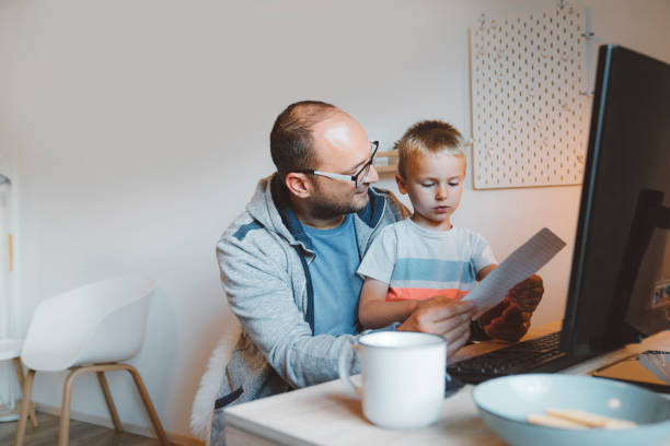 istock Father helping his son with homework, while doing some of his own work 1226913769