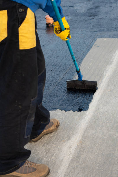 Worker applies bitumen mastic on the foundation stock photo