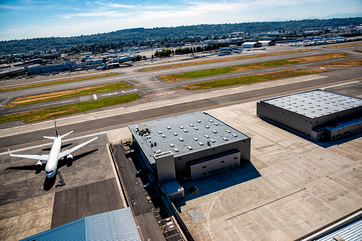 A plane parked adjacent a hangar and runways at Boeing Field, King County Airport near Seattle, Washington shot from a departing helicopter.